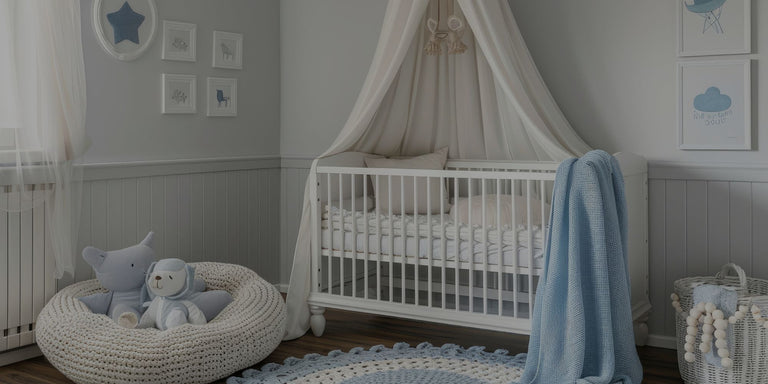 A styled baby nursery featuring a white wooden canopy crib with a cream fabric canopy, a light blue throw blanket, a white knit beanbag chair with plush toys, and a blue patterned rug on a wood floor.